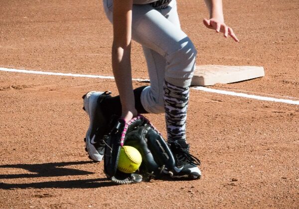 A softball player fields a ball near home plate